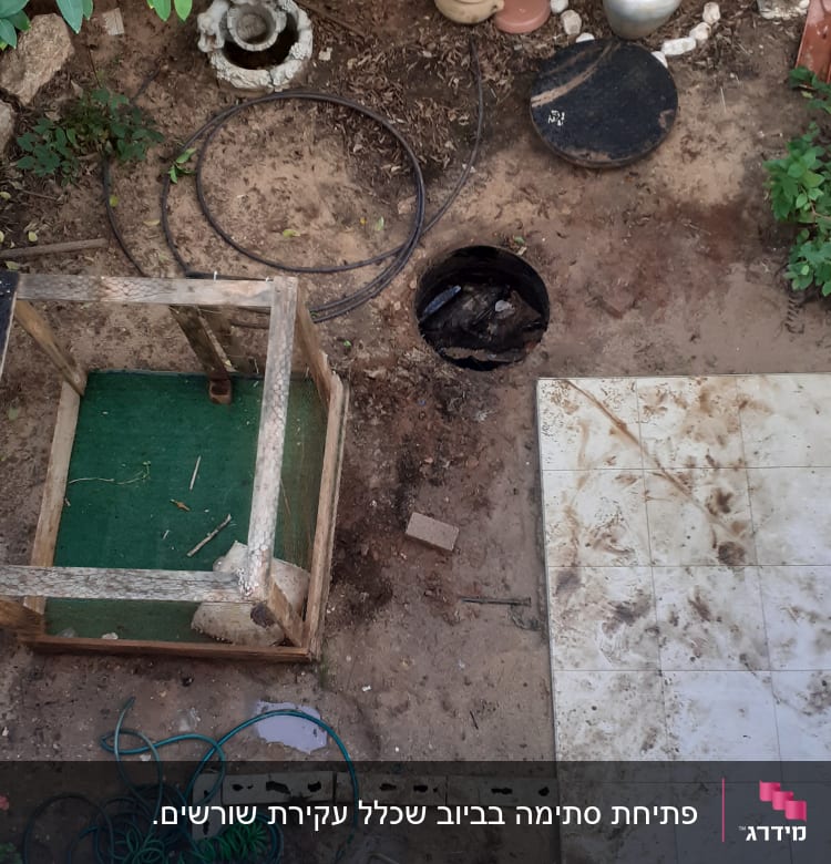 חצר עם מכסה ביוב פתוח וצינור ירוק